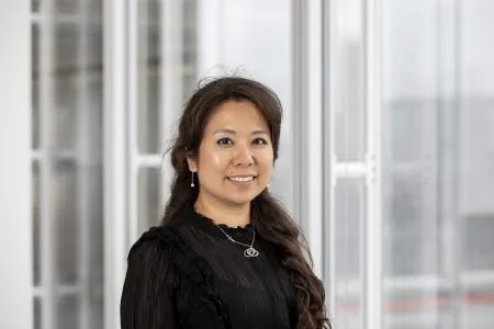 Jane Wakiwaka, head of sustainability, Real Estate Management and board director of the Better Buildings Partnership standing by a window inside a building